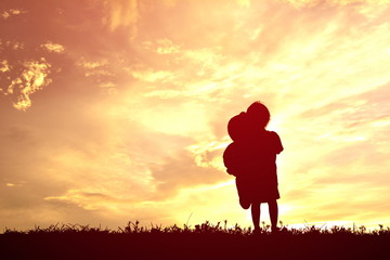 Silhouette little girl with teddy bear on sunset