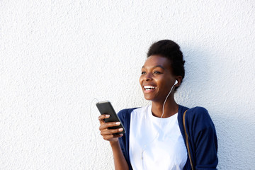 Cheerful young african woman listening music on smart phone