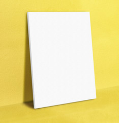 Blank white poster canvas frame leaning at yellow concrete paint
