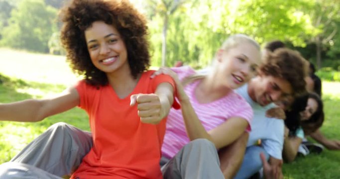 Group of casual young friends sitting in a row messing