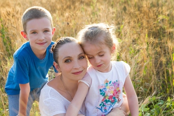 Fototapeta premium Mother with two children in golden wheat
