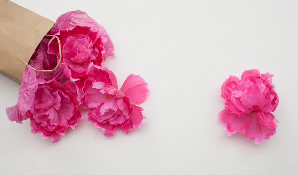 Feminine flat lay blog photo background featuring pink flowers tumbling from paper bag