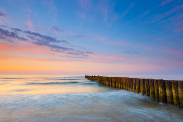 sunset on the beach with a wooden breakwater, long exposure