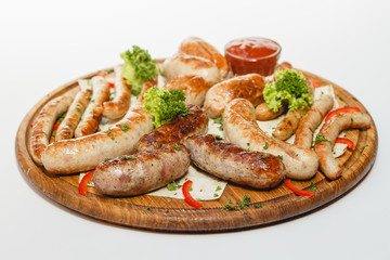 Different kind of grilled sausages on the wooden plate on white background