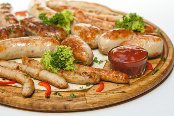 Different kind of grilled sausages on the wooden plate on white background