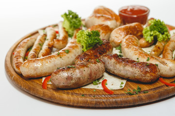 Different kind of grilled sausages on the wooden plate on white background