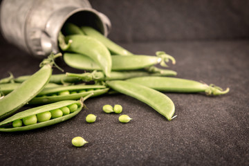 fresh green sweet peas  on black stone background