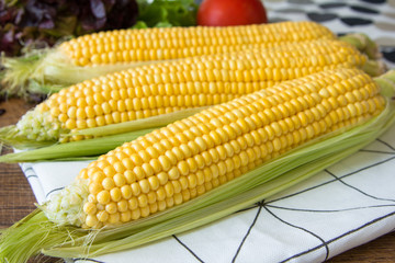 Ripe yellow corn cob on brown wooden board