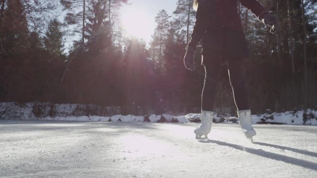 SLOW MOTION CLOSE-UP: Young ice skater spinning on frozen pond