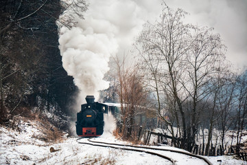 Vintage steam train puffing through countryside during wintertime