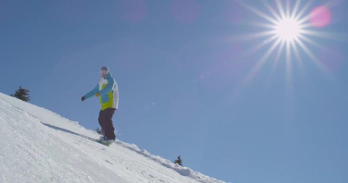 SLOW MOTION: Snowboarder jumps over camera on sunny winter day