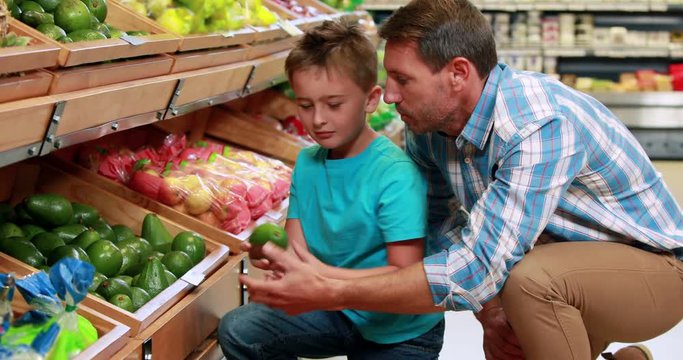 Father and son picking out pepper in supermarket