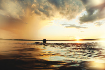 Man bathes in the lake at sunset. Beautiful sunset. Lens flare effect