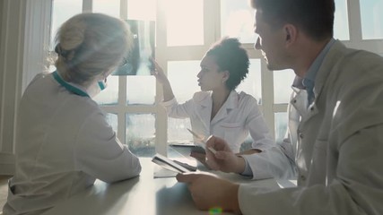 Healthcare, medical: Group of multi-ethnic doctors discuss and looking x-ray in a clinic or hospital