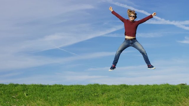 4K Happy man jumping for joy on grass, in slow motion, with space for text