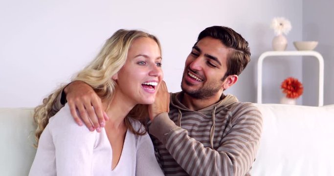 Man whispering a secret to his girlfriend on the couch 