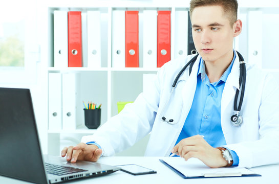 Portrait of young male doctor working on a laptop