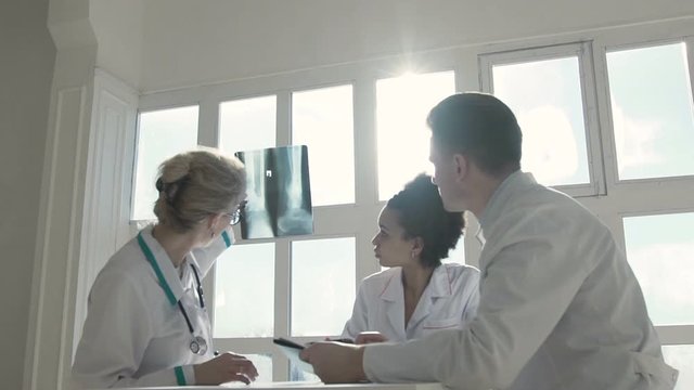 Healthcare, medical: Group of multi-ethnic doctors discuss and looking x-ray in a clinic or hospital. SLOW MOTION