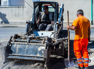 Worker checks the progress of the Milling of asphalt for road reconstruction accessory for skid steer