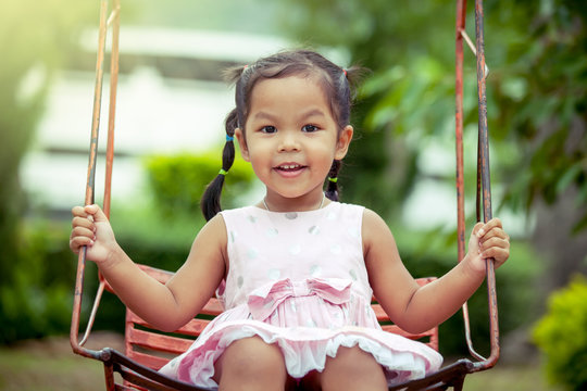 Child asian girl having fun to play swing in playground