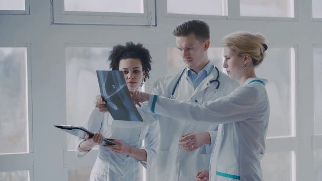 Healthcare, medical: Group of multi-ethnic doctors discussing and looking x-ray in a clinic or hospital. UHD 4K