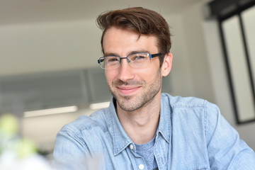 Casual smiling guy with eyeglasses sitting at home