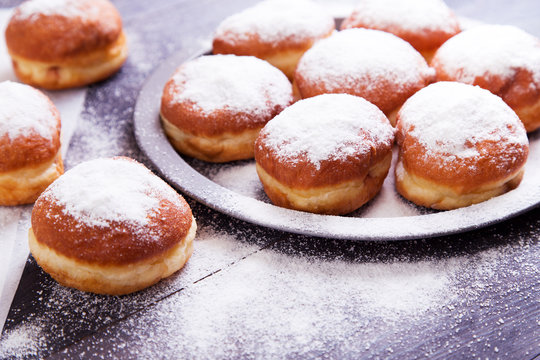 German donuts - berliner with jam and icing sugar in a tray on a dark wooden background. Space for text