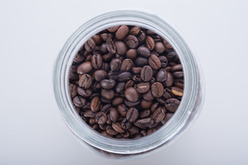the glass bottle of coffee bean on white background. Selective focus on the coffee bean inside the bottle