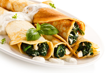 Crepes with spinach and feta cheese on white background 