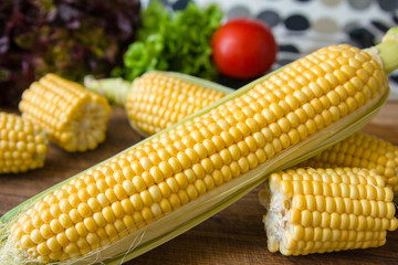 Ripe yellow corn cob on brown wooden board