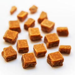 Salted caramel pieces and sea salt close up over white backgroun