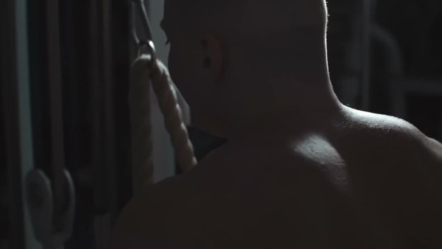 Rear view of man using cable crossover machine in the gym while training