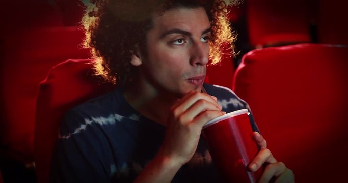 Young man watching a movie at the cinema 