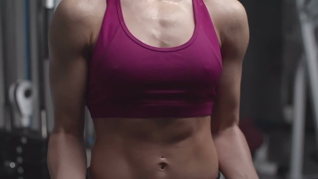 Slow motion shot of woman with perfect body doing basic biceps curl with dumbbells