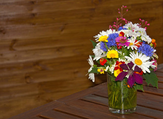 Bouquet of wild flowers on the table with a wooden background. Concept. black background, bright bouquet