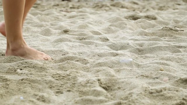 Women's feet are on the sand. Sand, sea, beautiful legs. Girl walking on the beach. 
