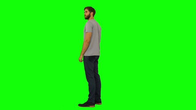 Casual man standing and looking around on green screen background