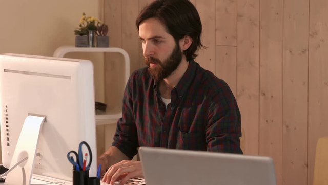 Casual hipster designer working on a computer at the office