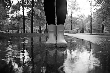 feet in rubber boots rain puddle city