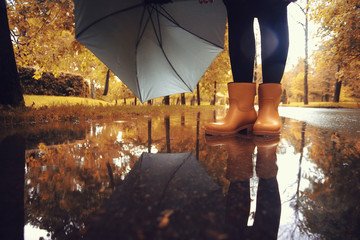 feet in rubber boots rain puddle city