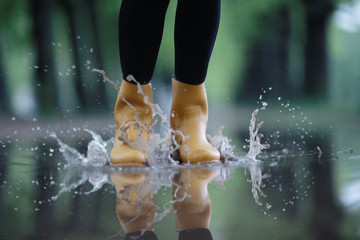 feet in rubber boots rain puddle city