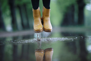 feet in rubber boots rain puddle city