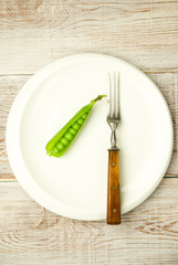 Green pea pod on the big white plate.