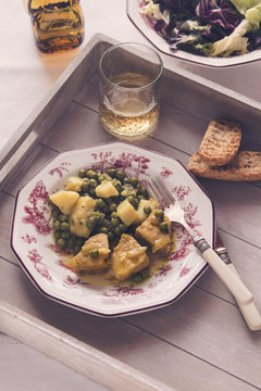 Fresh hake in sauce with potatoes and peas in a table set served
