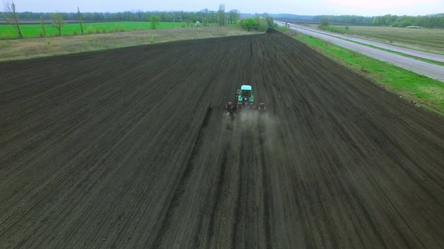 Tractor in a field brings fertilizer into the soil. Early spring. aerial survey 4k