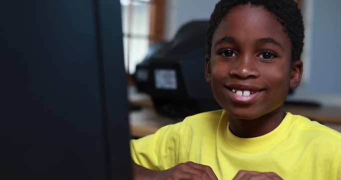 Little boy smiling at camera during computer class in elementary school