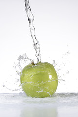 Agua cayendo sobre una manzana verde