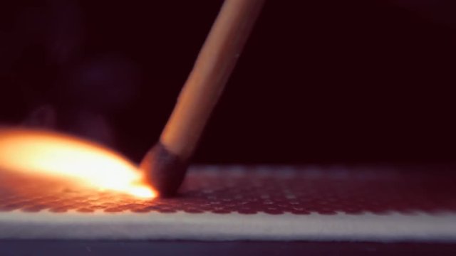 The match moves on the side of the matchbox and light the fire. Macro
