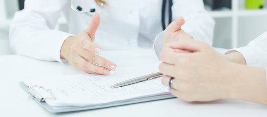 Young doctor explains how to fill out a medical form. Partnership, trust and medical ethics concept