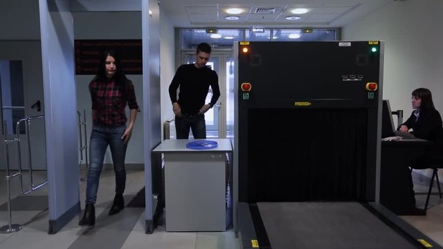 A man and a woman pass through a metal detector at airport.